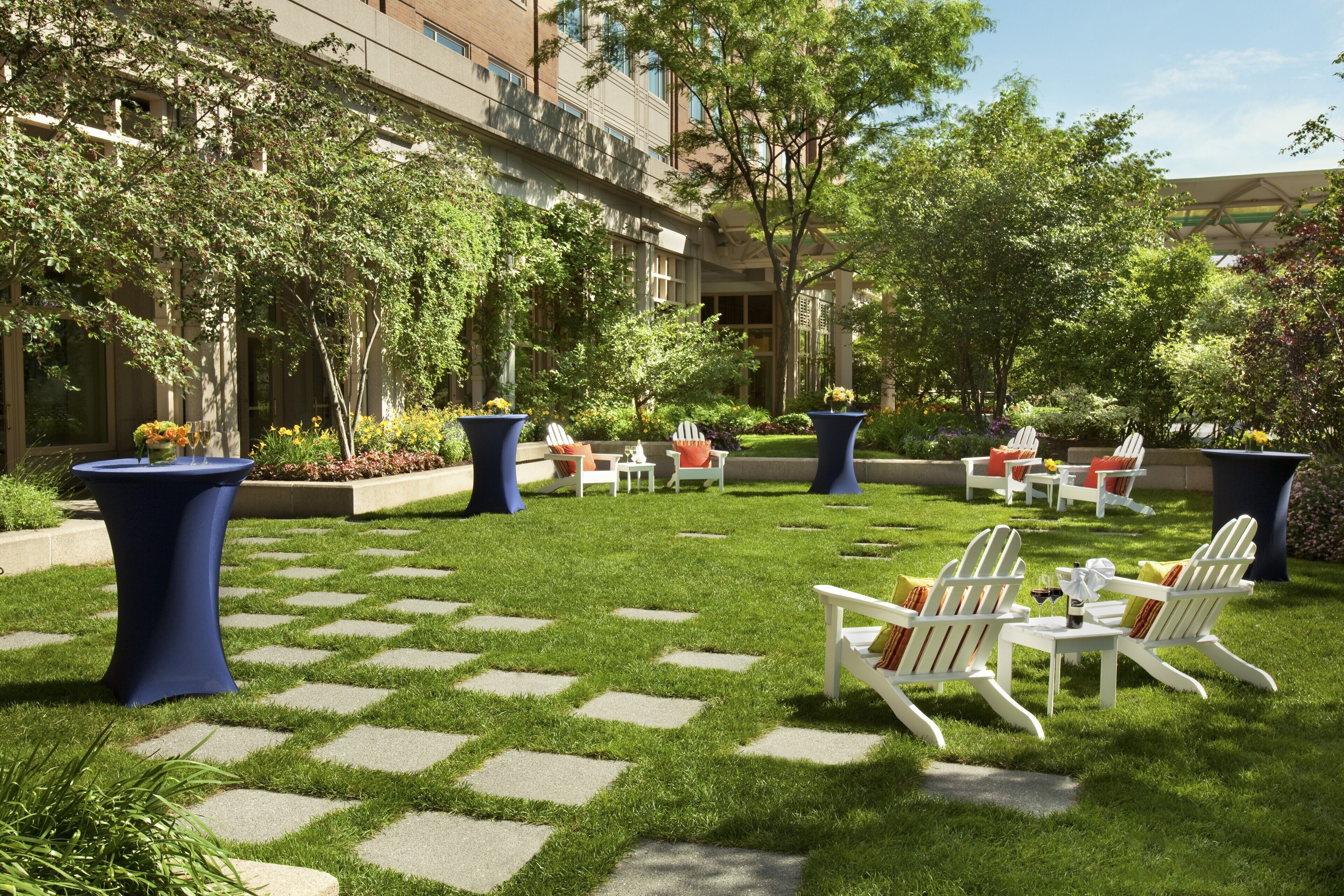 A courtyard with outdoor seating, greenery, and a building in the background.