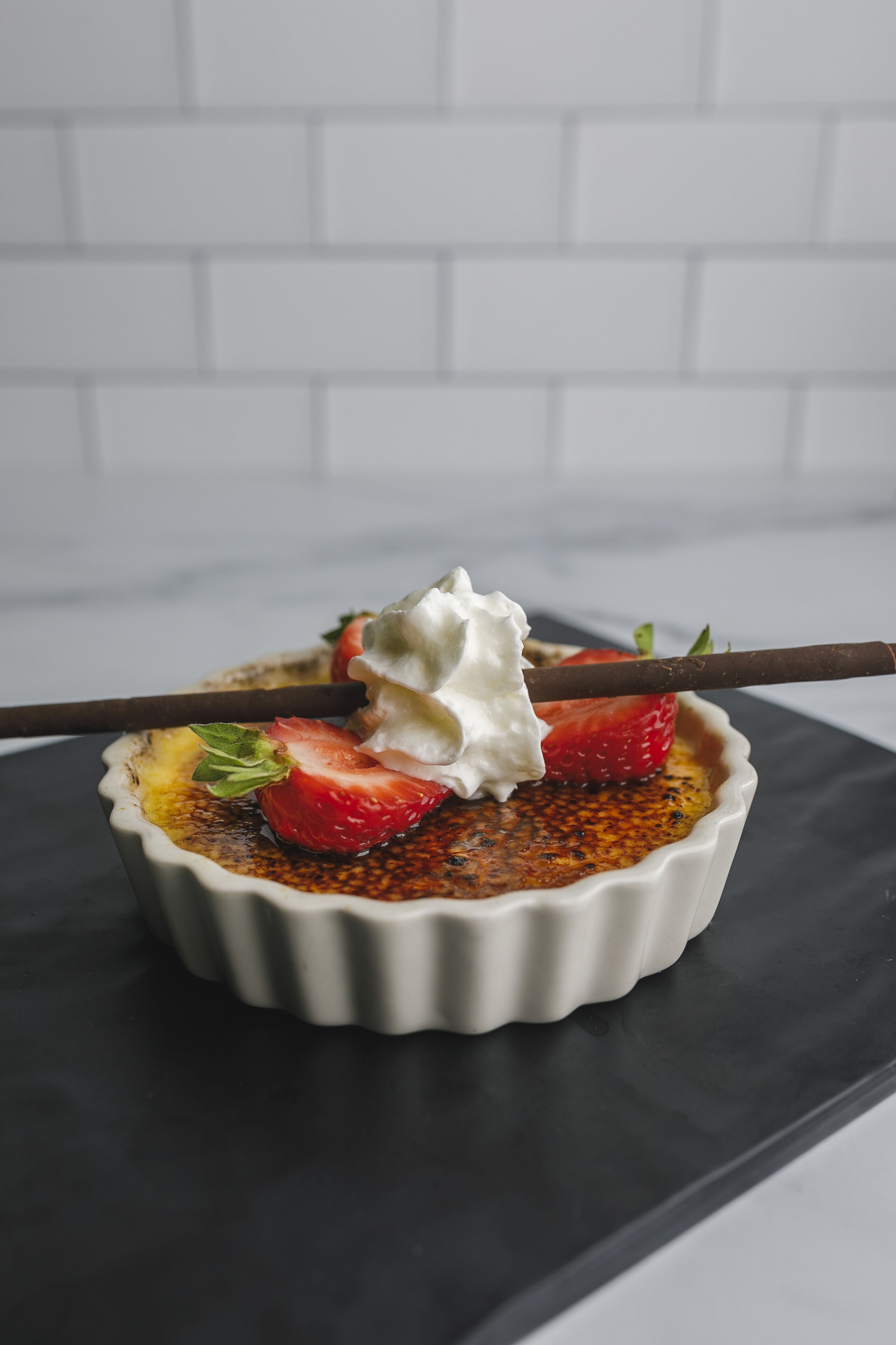 Un postre en un recipiente blanco sobre una superficie negra.