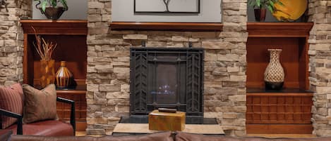 A cozy living room with a stone fireplace, leather sofa, and decorative items.