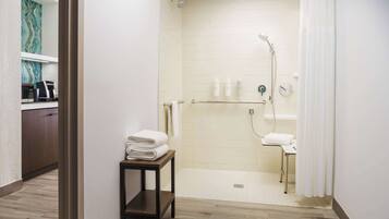 A modern bathroom with a walk-in shower, a small table with towels, and a visible sink.