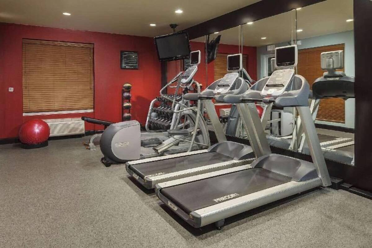 A gym with treadmills, elliptical machines, and exercise balls.