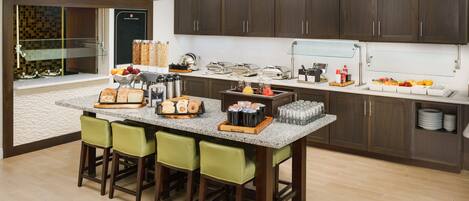 Una cocina moderna con armarios de madera oscura, encimera de granito y una isla central con taburetes de bar.