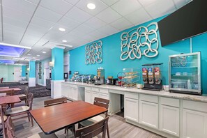 A hotel dining area with a buffet counter, seating arrangements, and decorative wall art. - Clarion Inn Des Moines Airport (Des Moines)
