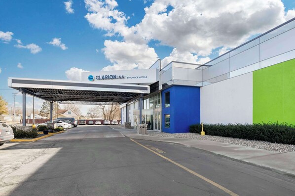A hotel entrance with a covered parking area, a clear sky, and a sign for Clarion Inn by Choice Hotels.