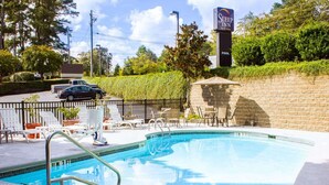 Un espace piscine avec des chaises longues et un panneau indiquant « Sleep Inn & Suites ».
