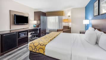 A hotel room with a bed, a TV, a desk, a chair, and a window with curtains.
