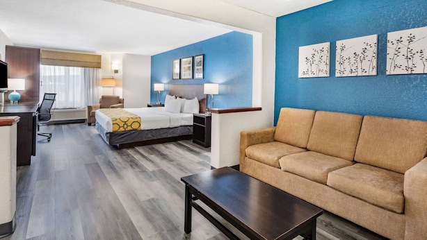 Una habitación de hotel con cama, sofá, escritorio y televisión.