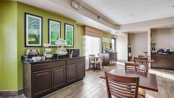 Una cocina moderna con una isla central, comedor con sillas de madera y paredes verdes.