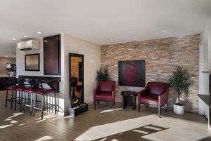 Un moderno vestíbulo de hotel con una pared de piedra, una chimenea y zonas de estar.