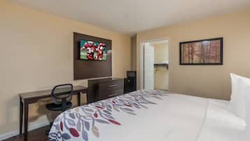 Een hotelkamer met een bed, een bureau met stoel, een televisie aan de muur en een deur naar een kast.