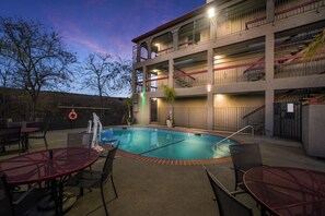 Piscina com um terraço ao redor, incluindo mesas e cadeiras.