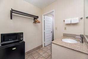 A compact bathroom with a built-in microwave, a sink with a granite countertop, and a towel rack with hangers. - Red Roof Inn Stockton (Stockton)