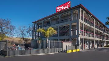 Un edificio de varios pisos con un llamativo letrero de Red Roof, que cuenta con balcones y una entrada con portón.