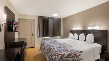 A hotel room with a large bed, a desk, and a TV.