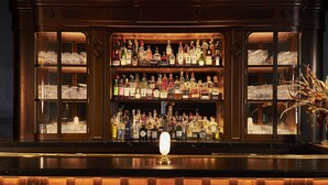 A bar with multiple shelves of liquor bottles and glasses. - The Vanderbilt, Auberge Collection (Newport)