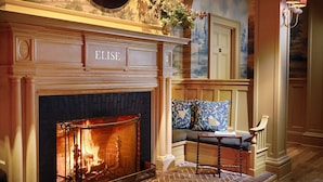 A fireplace with a sign reading "ELISE," a bench with patterned cushions, and a wall with a mural. - The Vanderbilt, Auberge Collection (Newport)