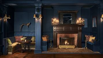 Una habitación con chimenea, sofá, mesa y apliques de pared.