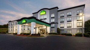 A Wingate Inn hotel with a modern design, featuring a prominent green and white color scheme, multiple windows, and a well-lit entrance. - Wingate by Wyndham Charlotte Speedway/Concord (Concord)