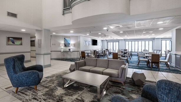 A spacious lobby with a modern design, featuring a large sofa, a coffee table, and a blue armchair. - Wingate by Wyndham Charlotte Speedway/Concord (Concord)