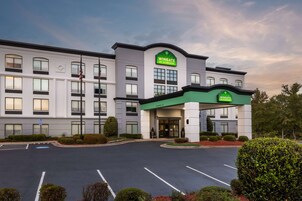 Un hotel Wingate con fachada moderna, estacionamiento y jardines bien cuidados.