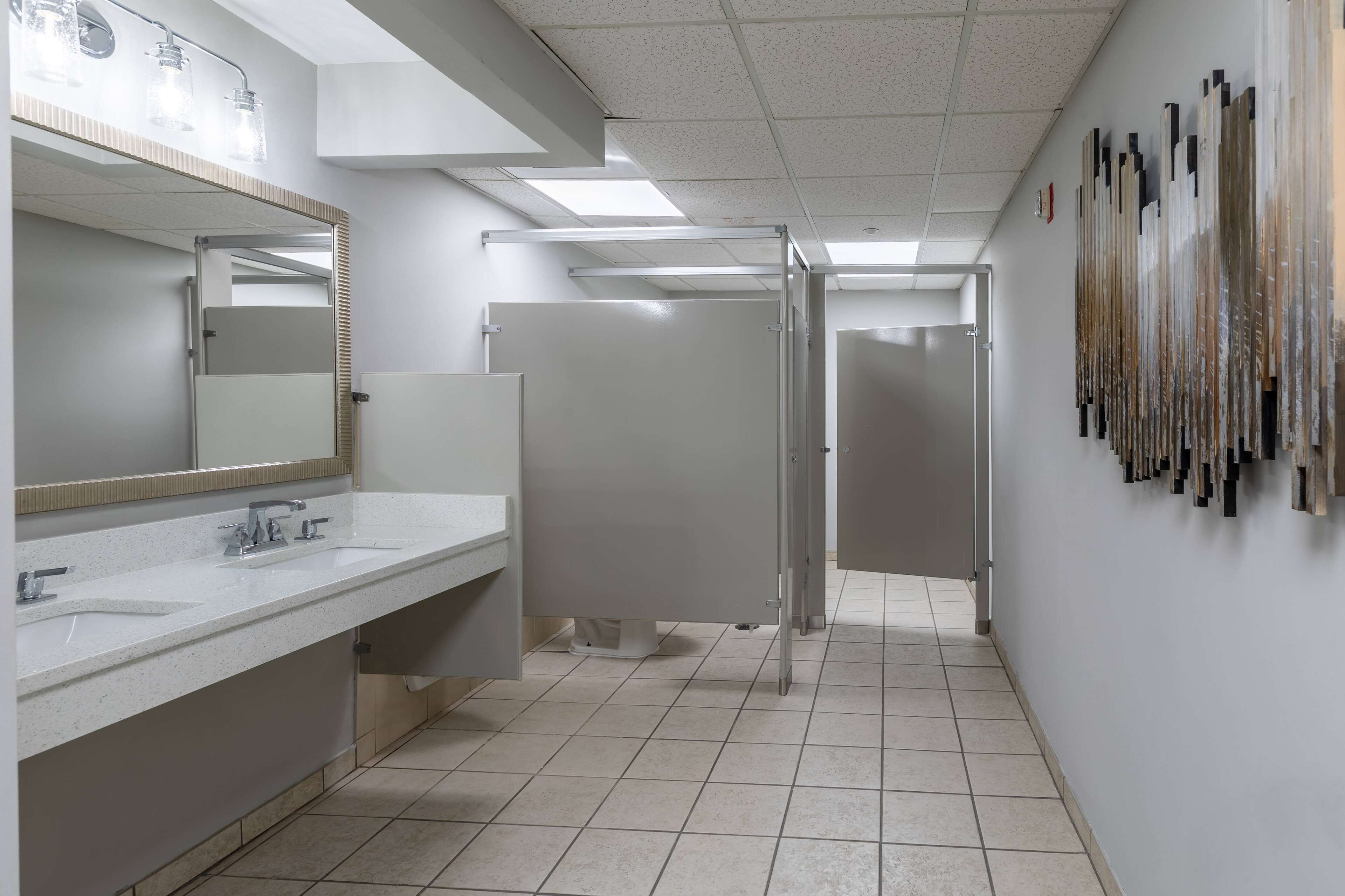 Ein modernes Badezimmer mit zwei Waschbecken, einem großen Spiegel und einer Duschkabine.