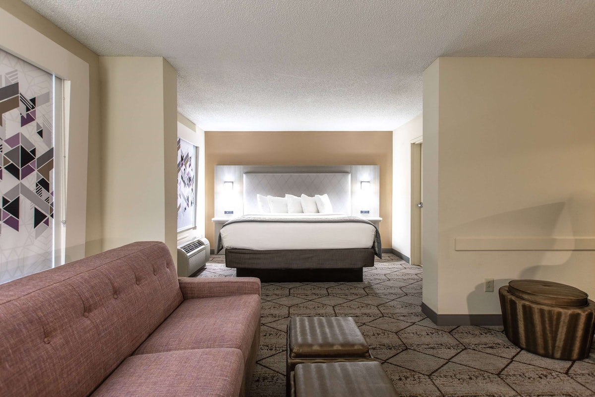 Une chambre d’hôtel avec un grand lit, un canapé, une petite table et un tapis à motifs.