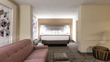 Una habitación de hotel con una cama grande, un sofá, una mesita y una alfombra estampada.