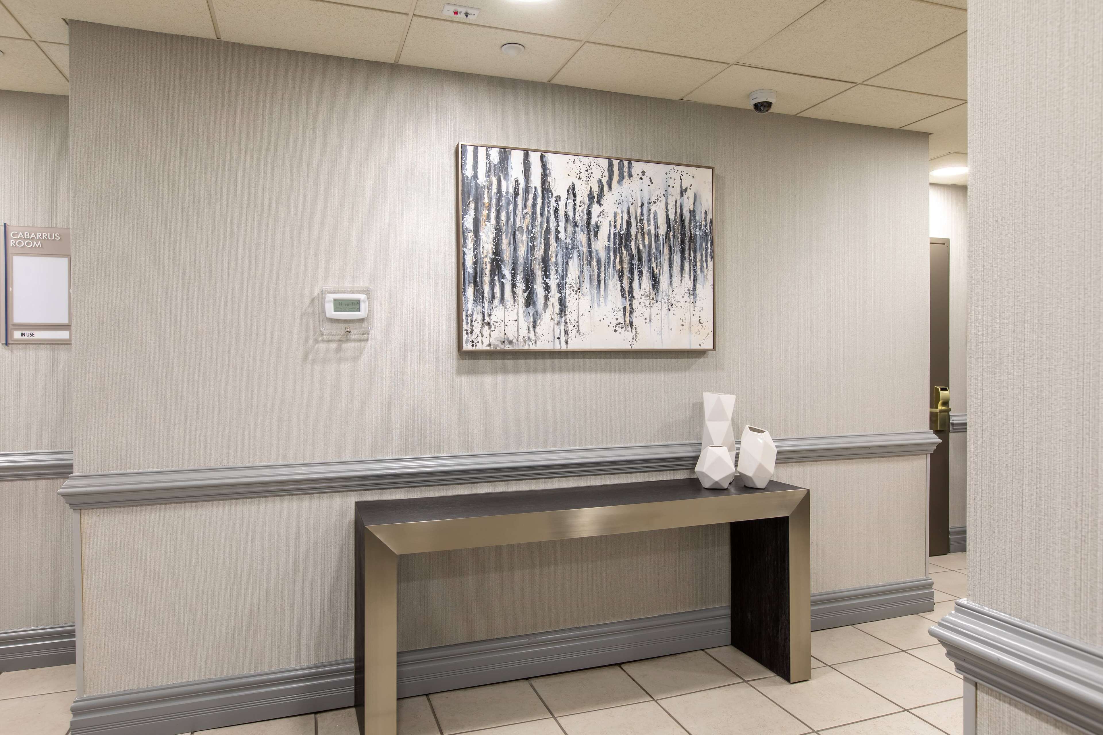 A hotel reception area with a modern reception desk, a wall-mounted artwork, and a sign indicating the room type.