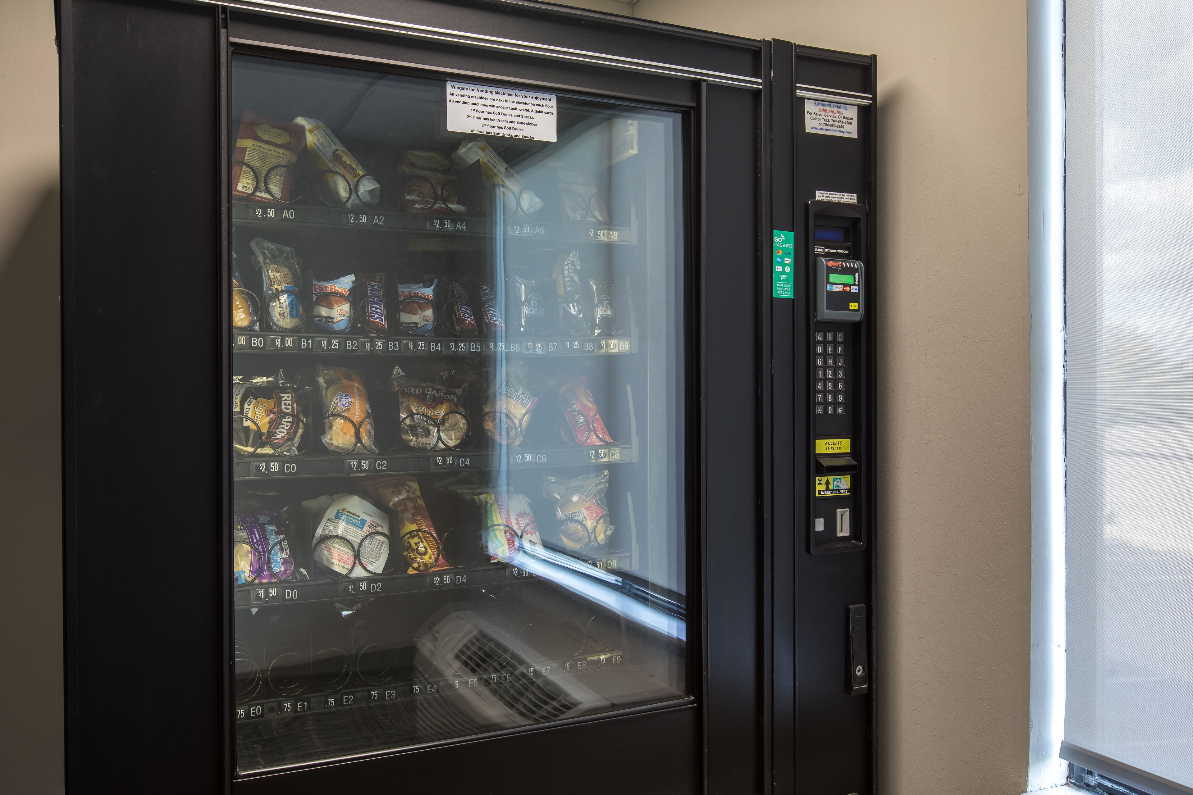 A vending machine with snacks and drinks, a payment keypad, and a coin slot.