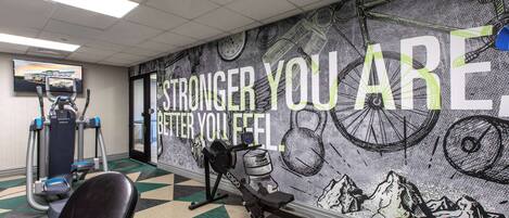 A gym with exercise equipment, a motivational mural, and a patterned floor.