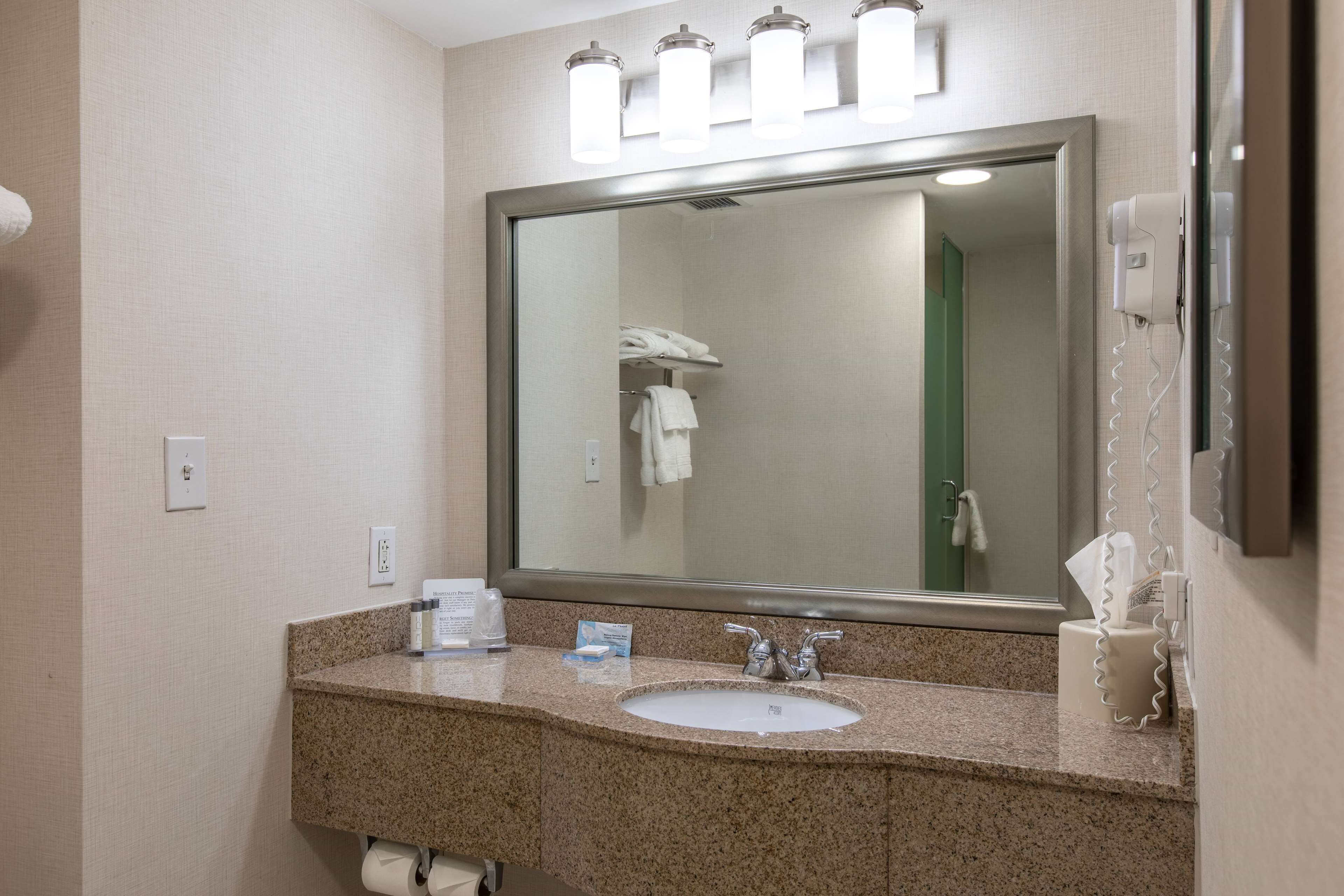 A bathroom with a granite countertop, a sink, a mirror, and a towel rack.