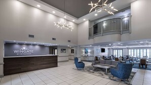 A spacious lobby with a reception desk labeled "Wingate by Wyndham," modern seating, and a high ceiling with recessed lighting. - Wingate by Wyndham Charlotte Speedway/Concord (Concord)