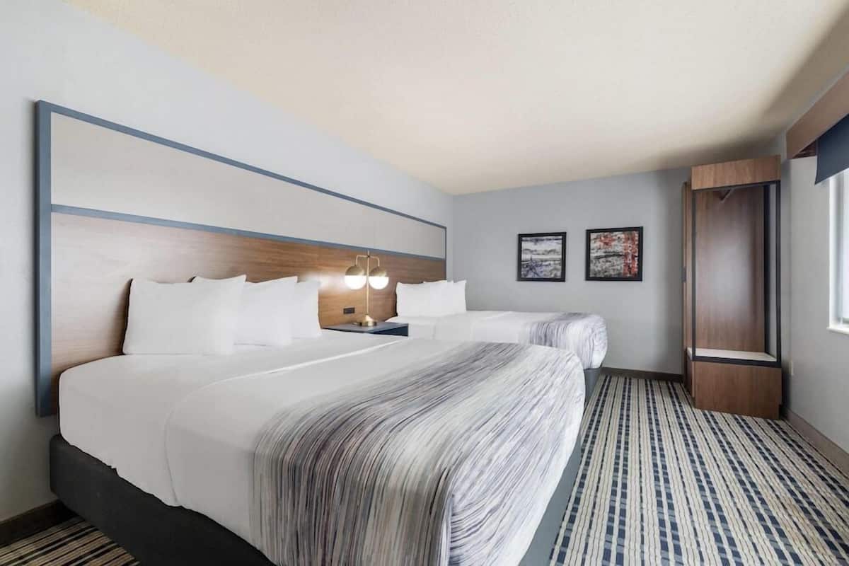 A hotel room with a large bed, bedside tables, a wardrobe, and a window.