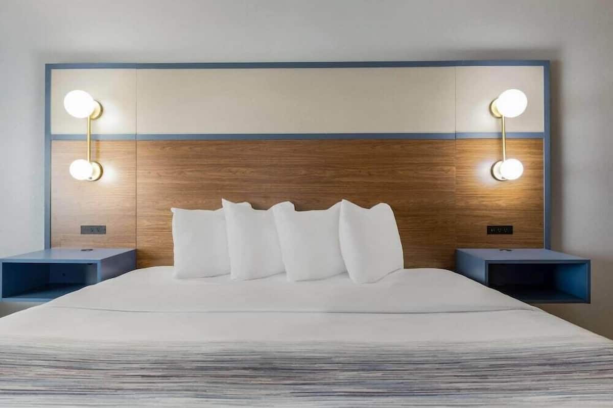 A hotel room with a large bed, two bedside tables, and wall-mounted lights.