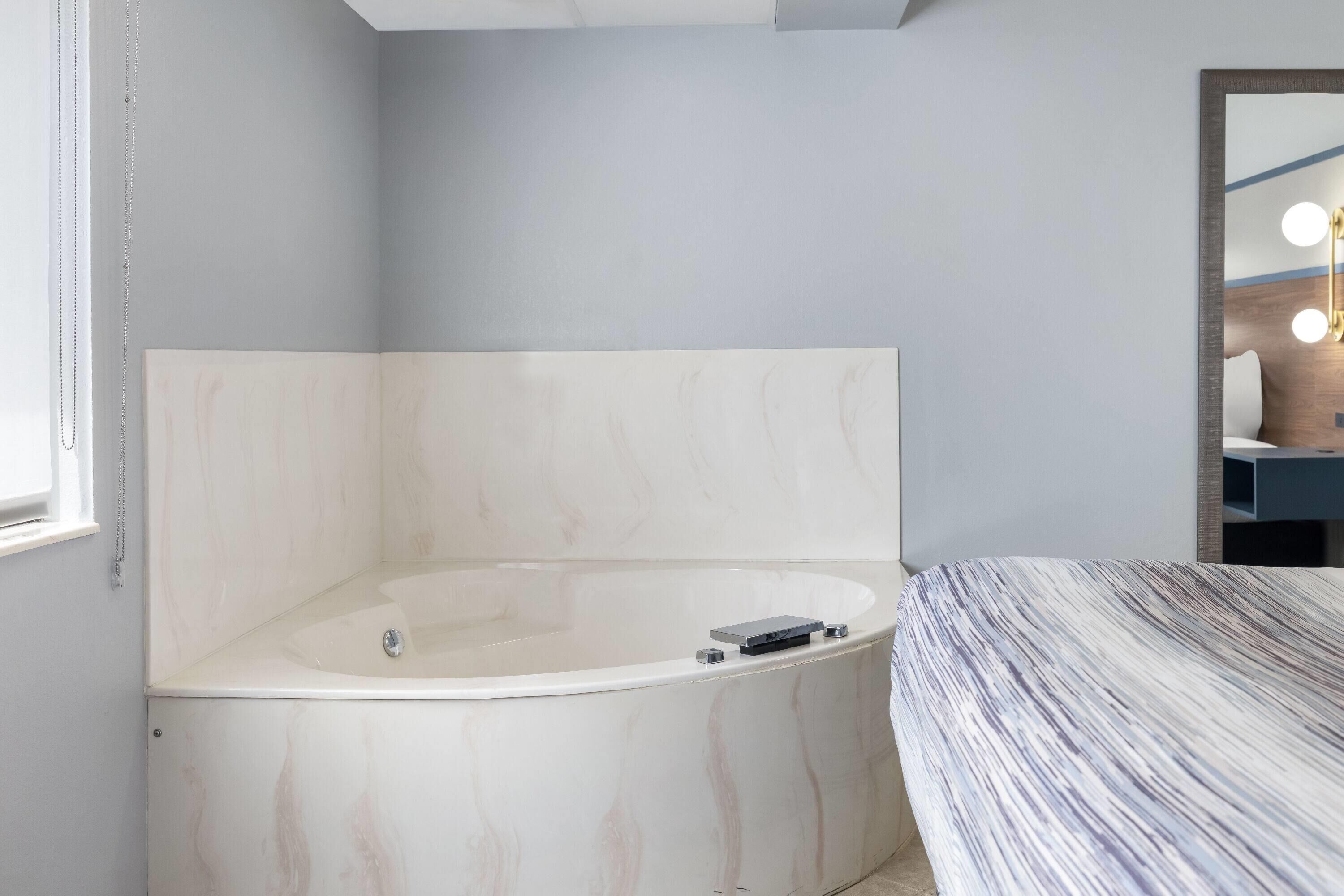 A modern bathroom with a freestanding bathtub, a large mirror, and a vanity with a light fixture.