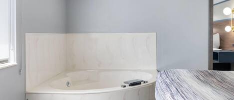 A modern bathroom with a freestanding bathtub, a large mirror, and a vanity with a light fixture.