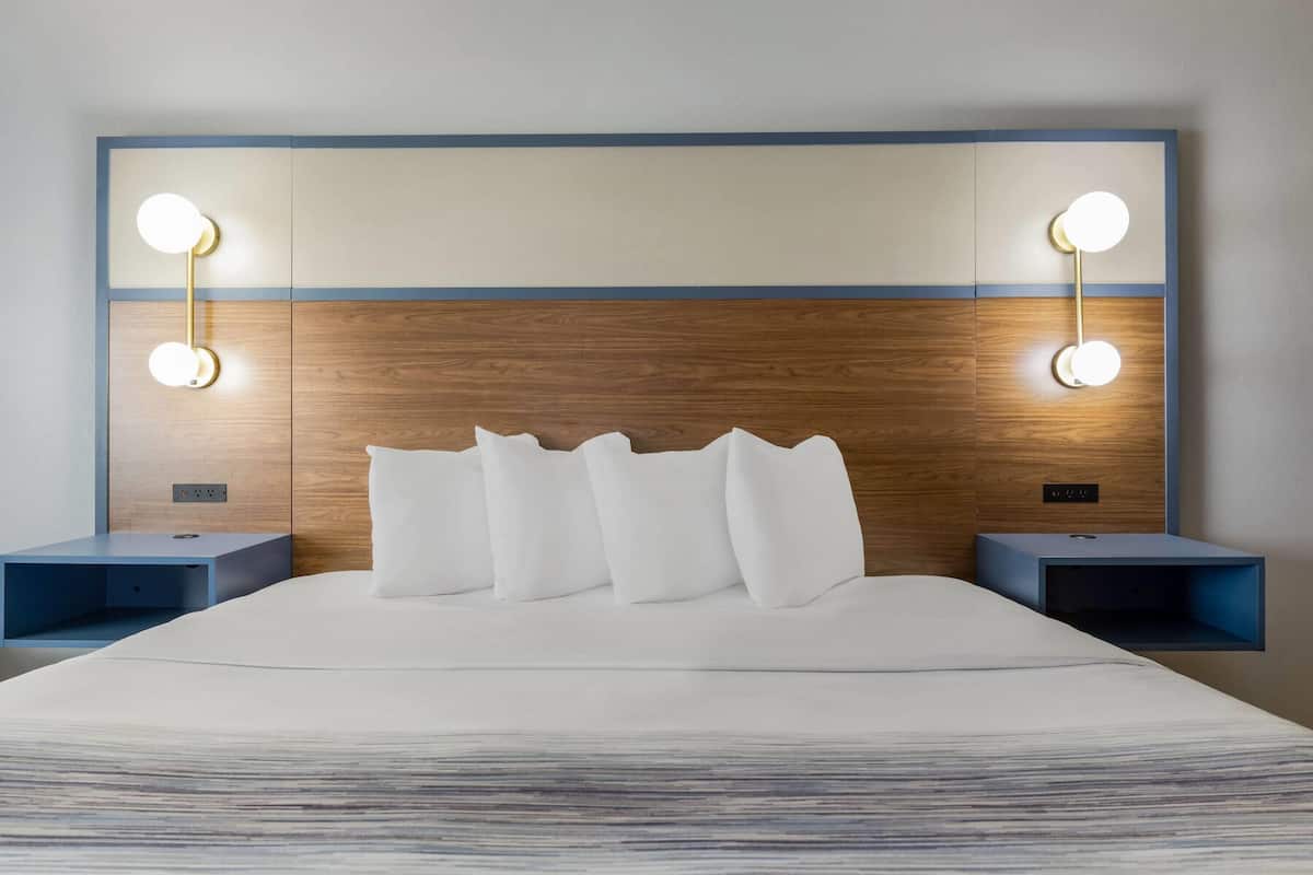 A modern hotel room with a large bed, two bedside tables, and wall-mounted reading lights.