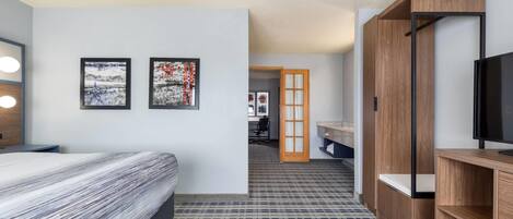 A hotel room with a bed, a TV, a desk, and a bathroom visible through an open door.