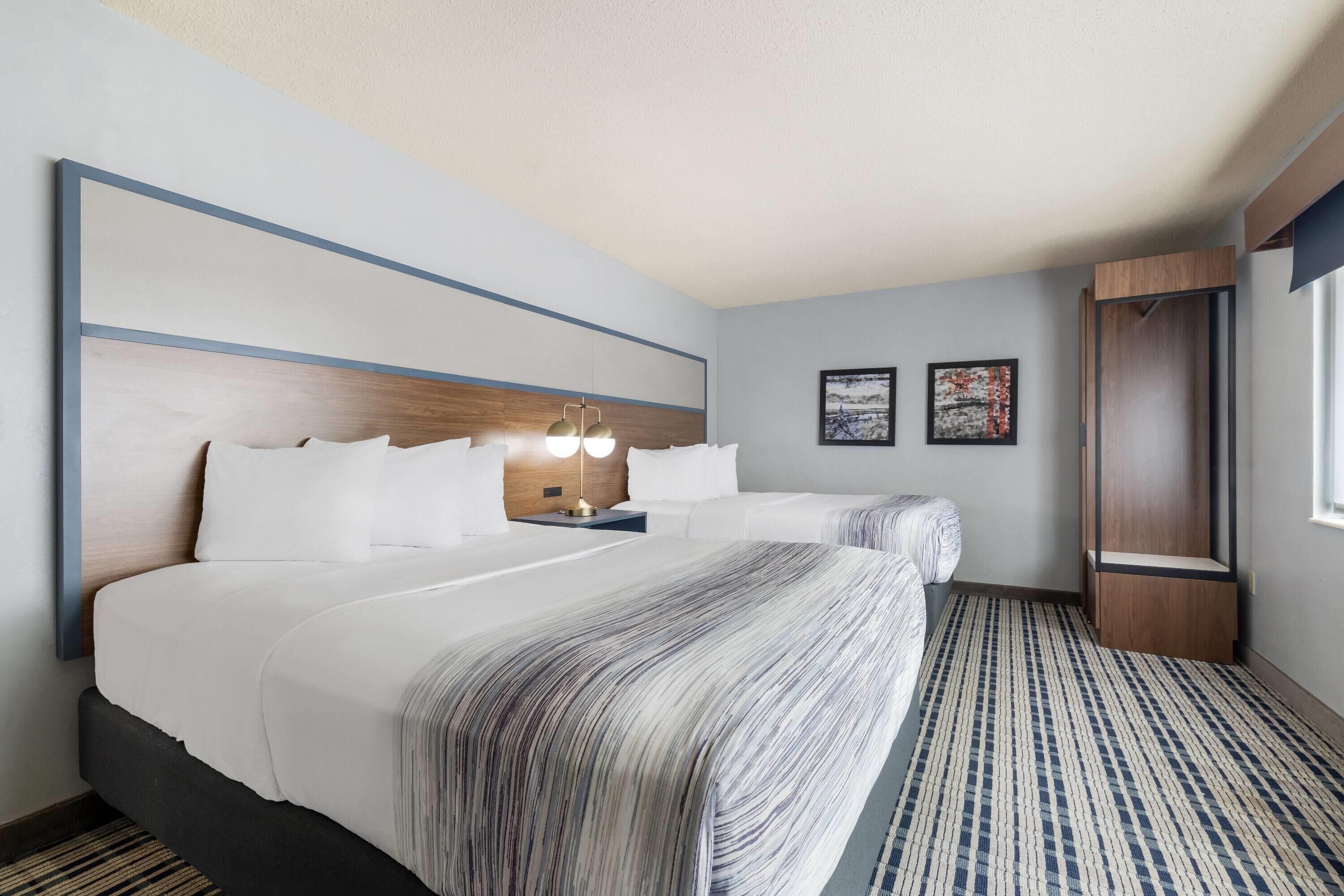 A hotel room with a large bed, bedside tables, a nightstand, a wardrobe, and a window.