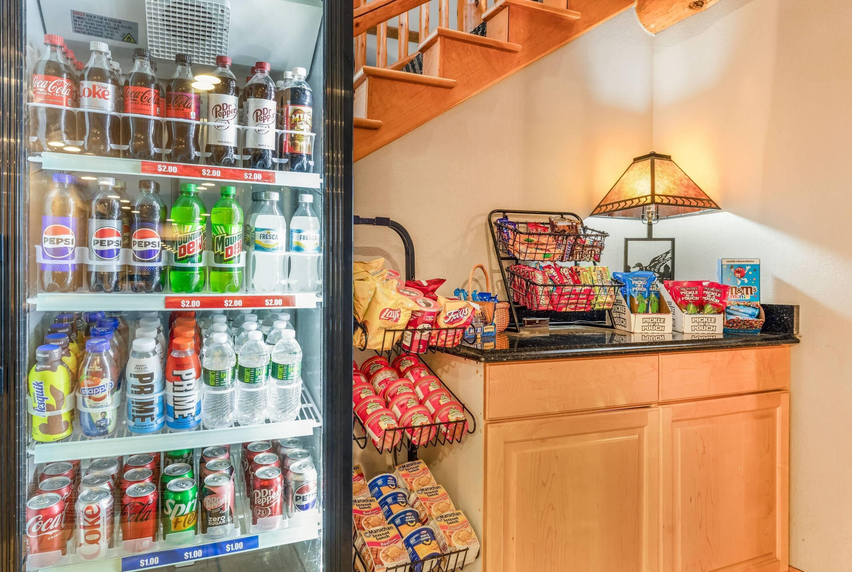 A vending machine stocked with various beverages and snacks, a lamp, and a bag of chips on a counter.