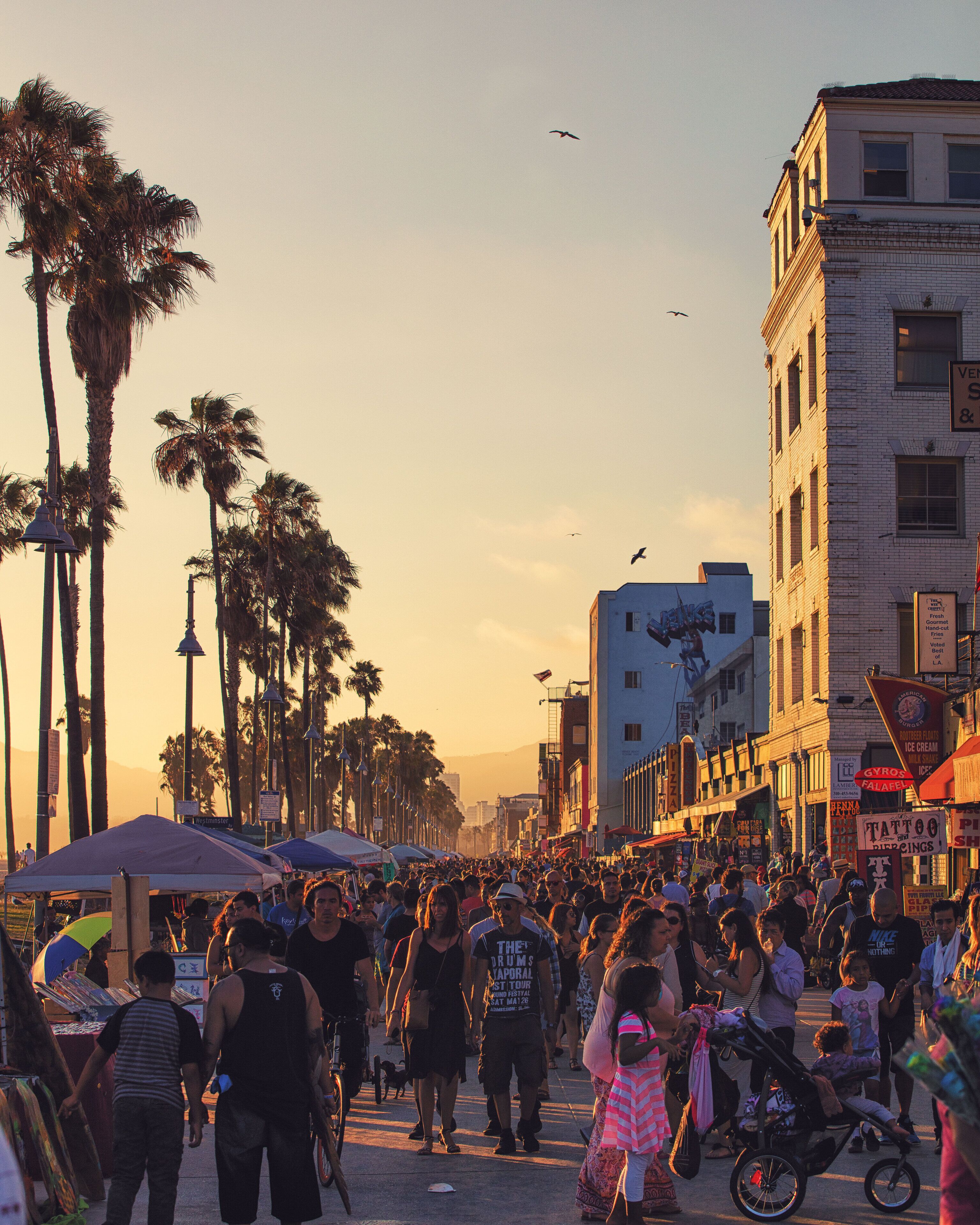 A crowded street scene with palm trees and buildings.