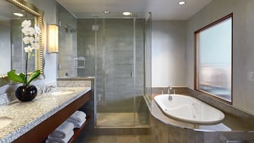 Un baño moderno con encimera de granito, un espejo grande, cabina de ducha y bañera independiente.