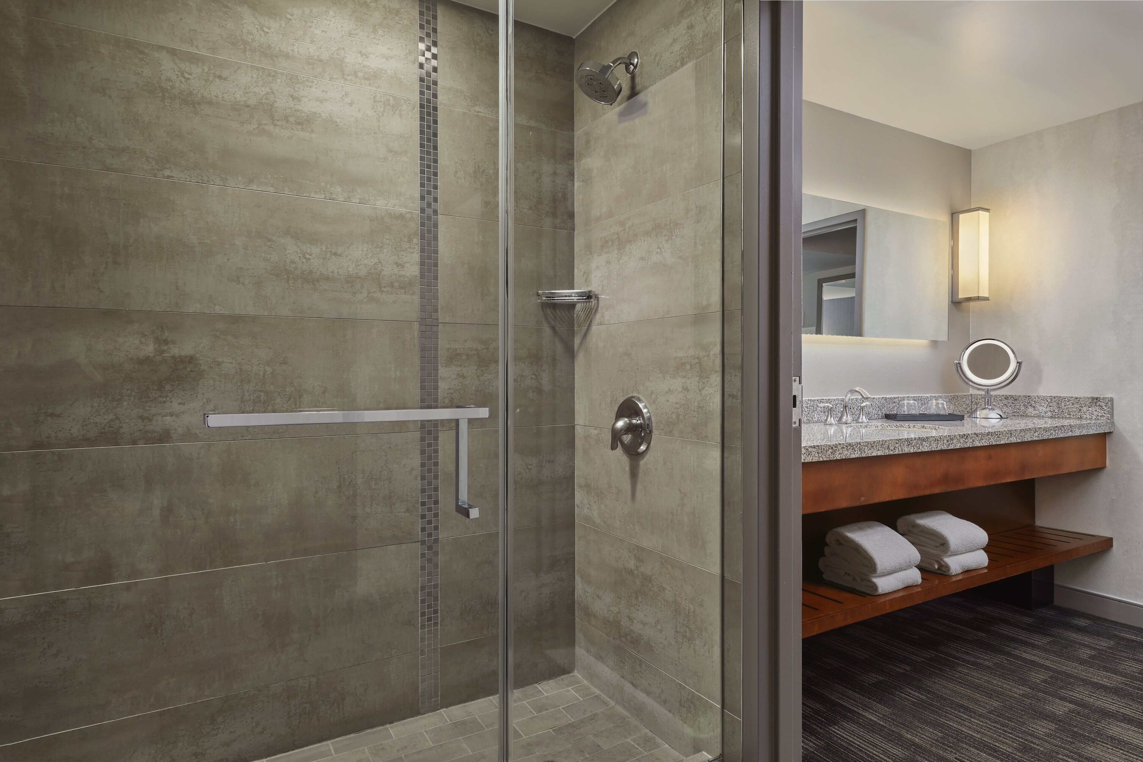 A modern bathroom with a glass shower enclosure, a vanity with a mirror, and a towel rack.