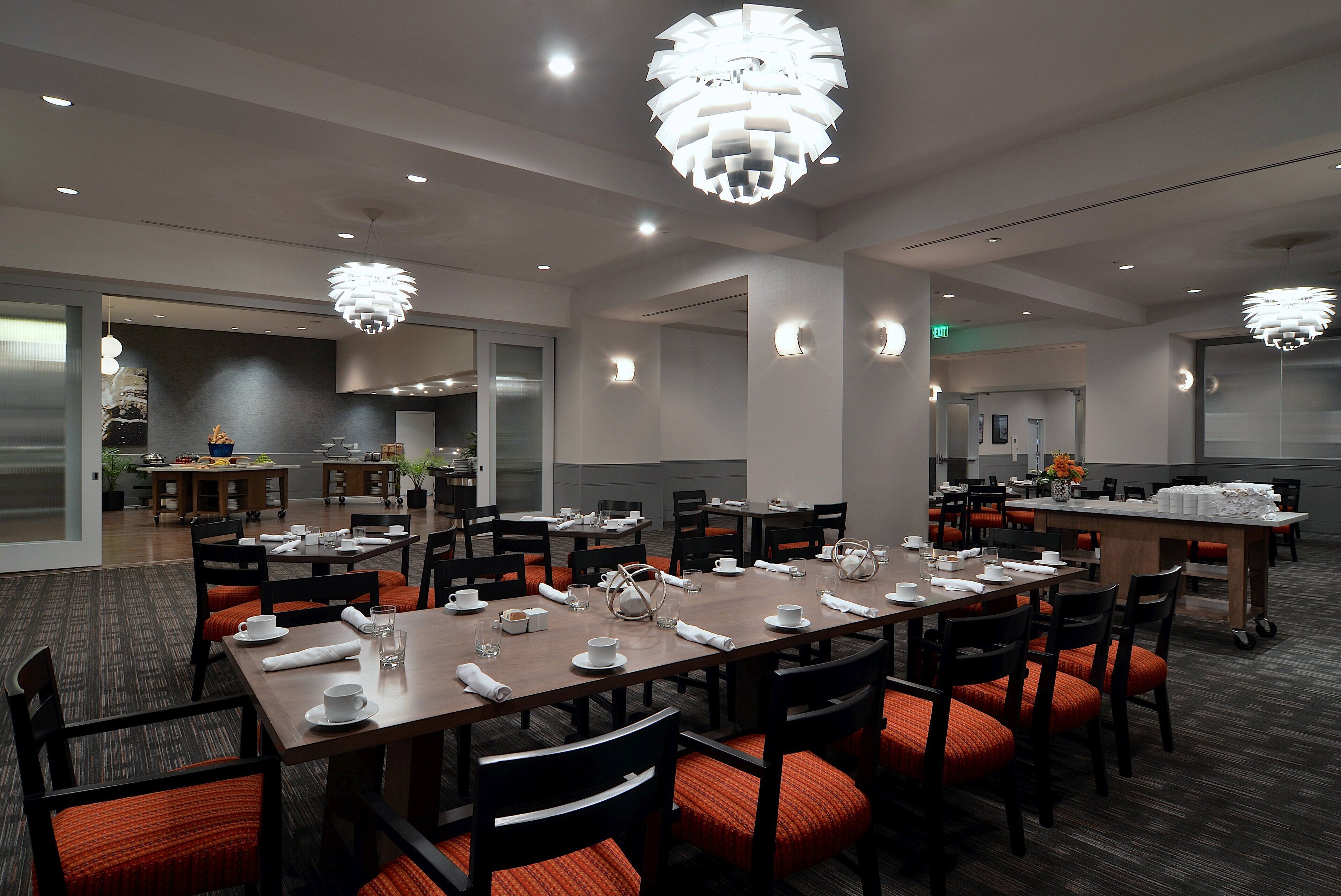 Un comedor de hotel con varias mesas dispuestas para comer, equipado con sillas y vajilla.