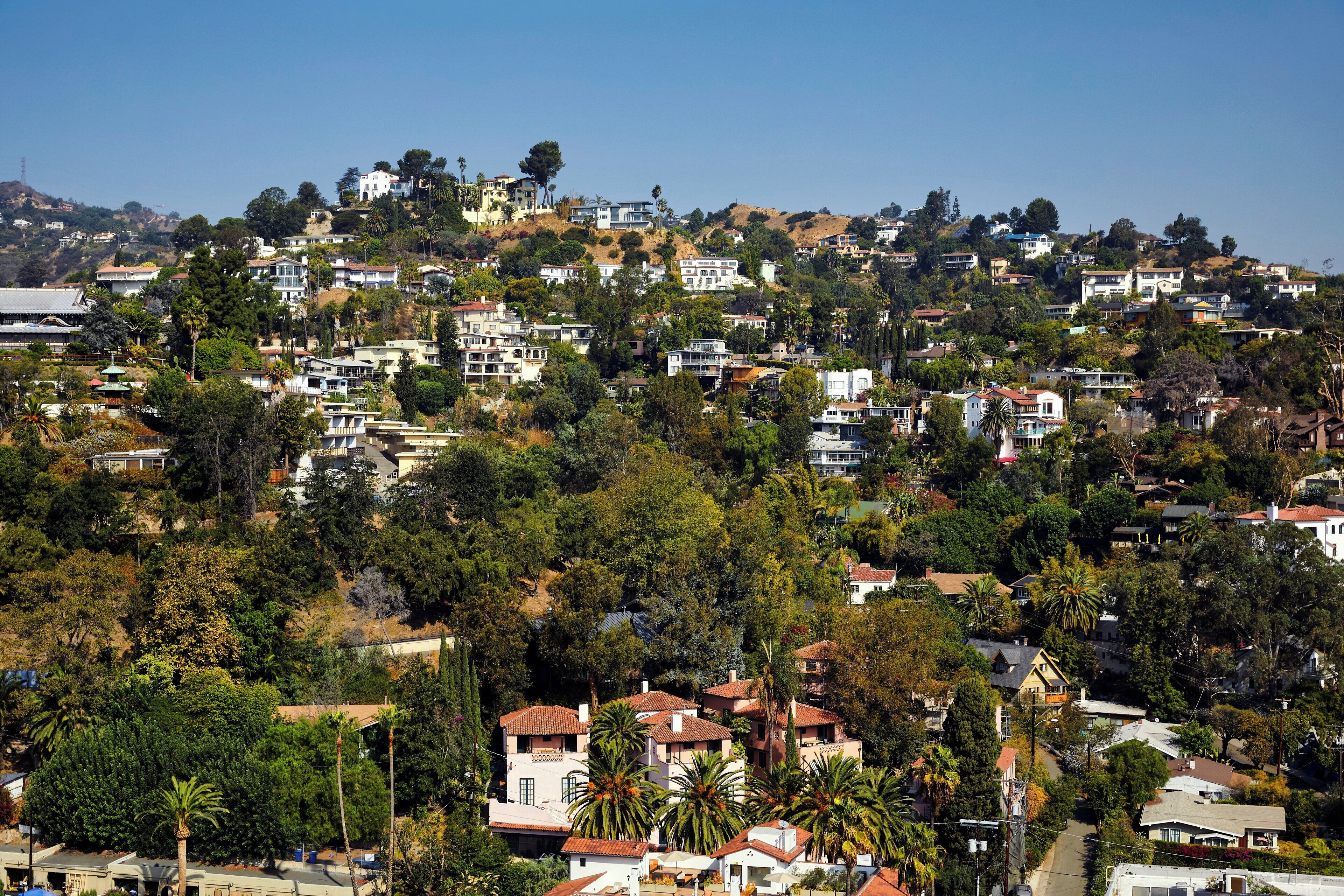A hillside residential area with houses, trees, and a clear sky.