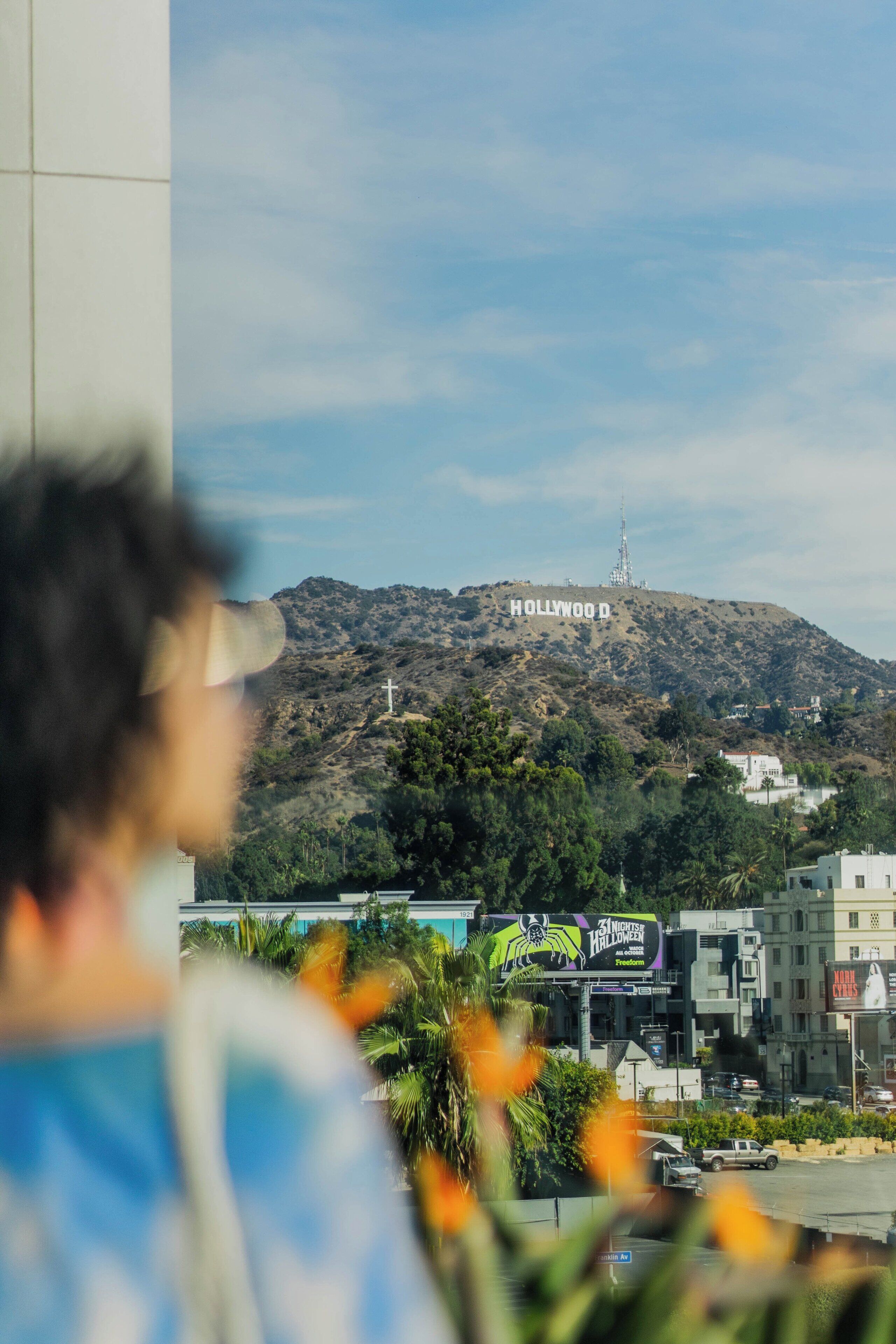 A view of the Hollywood sign with a building in the foreground.