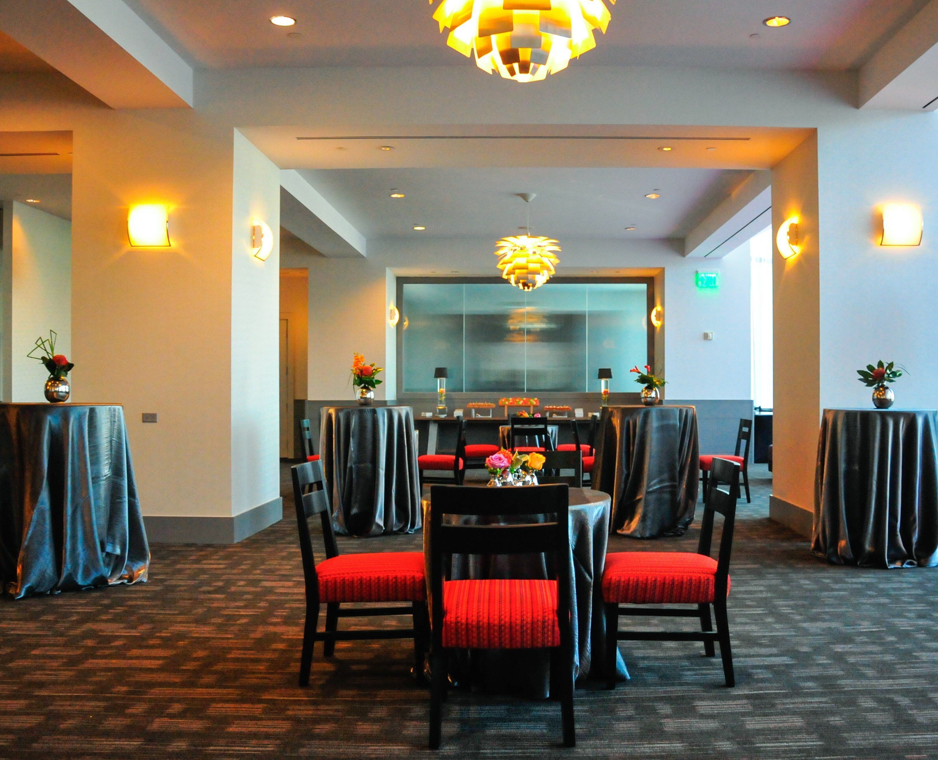 A restaurant with a central dining area, red upholstered chairs, and tables covered with dark cloths.