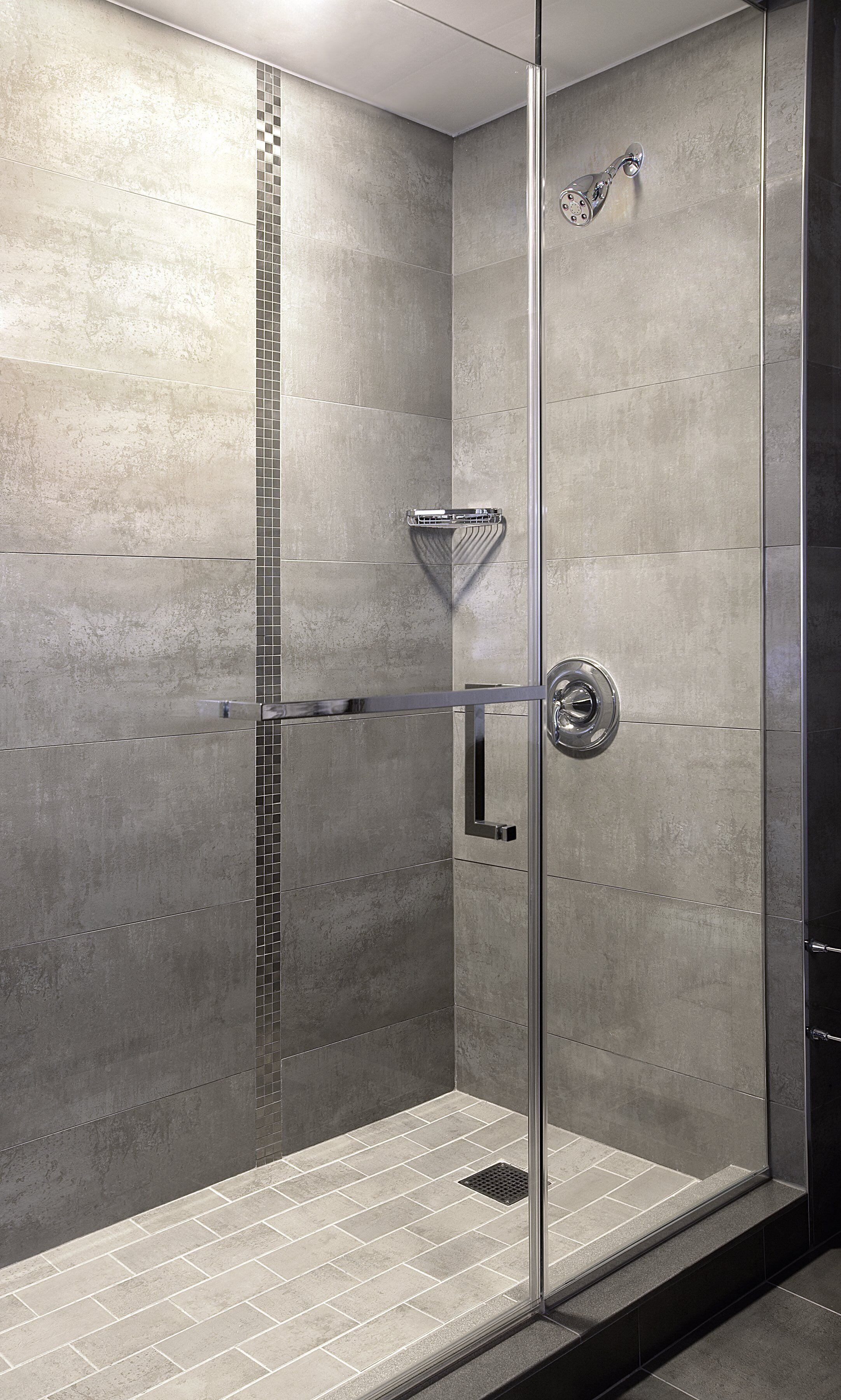 A modern shower with a glass door, a chrome showerhead, and a metal towel rack.