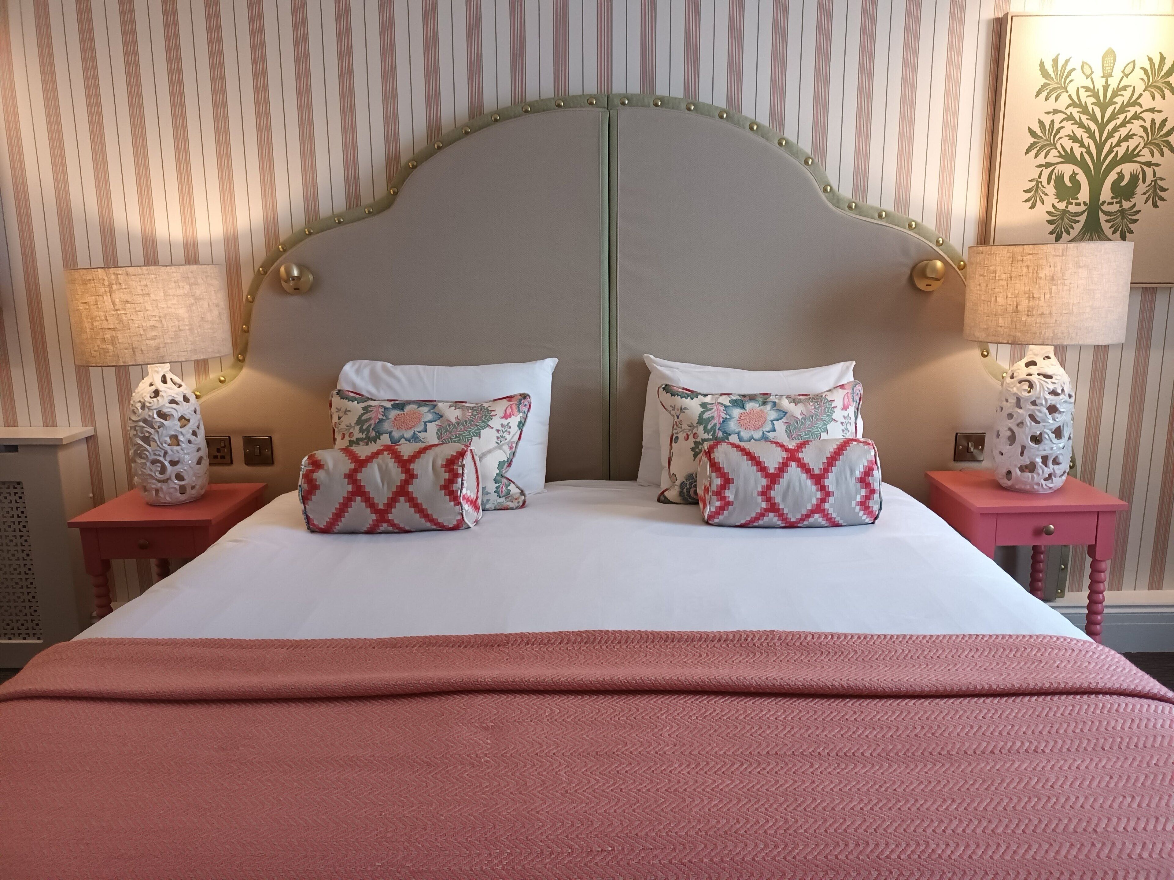 A bed with two pillows, a headboard, and two bedside tables with lamps.