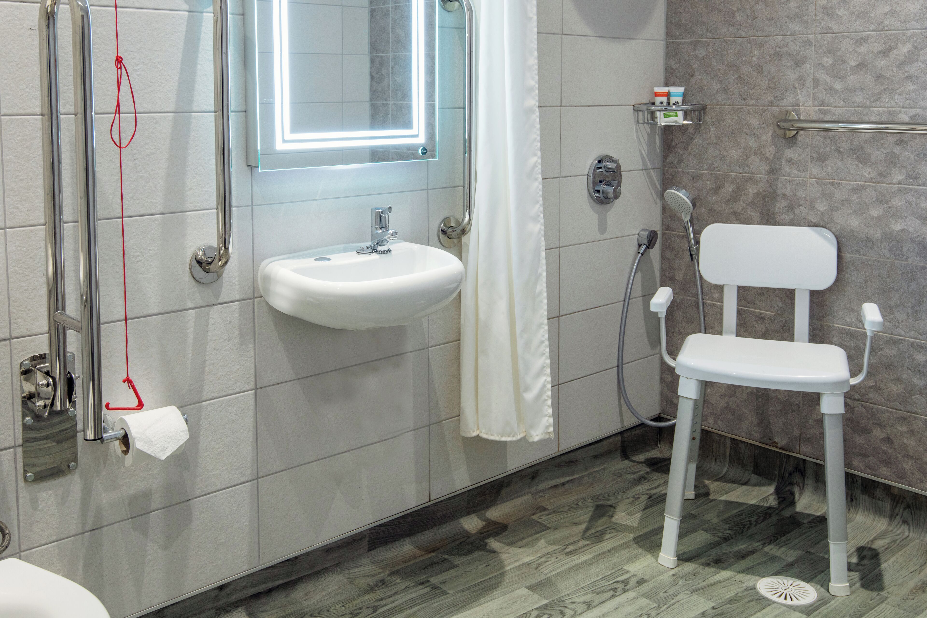 A bathroom with a white sink, a mirror, a shower, and a toilet.